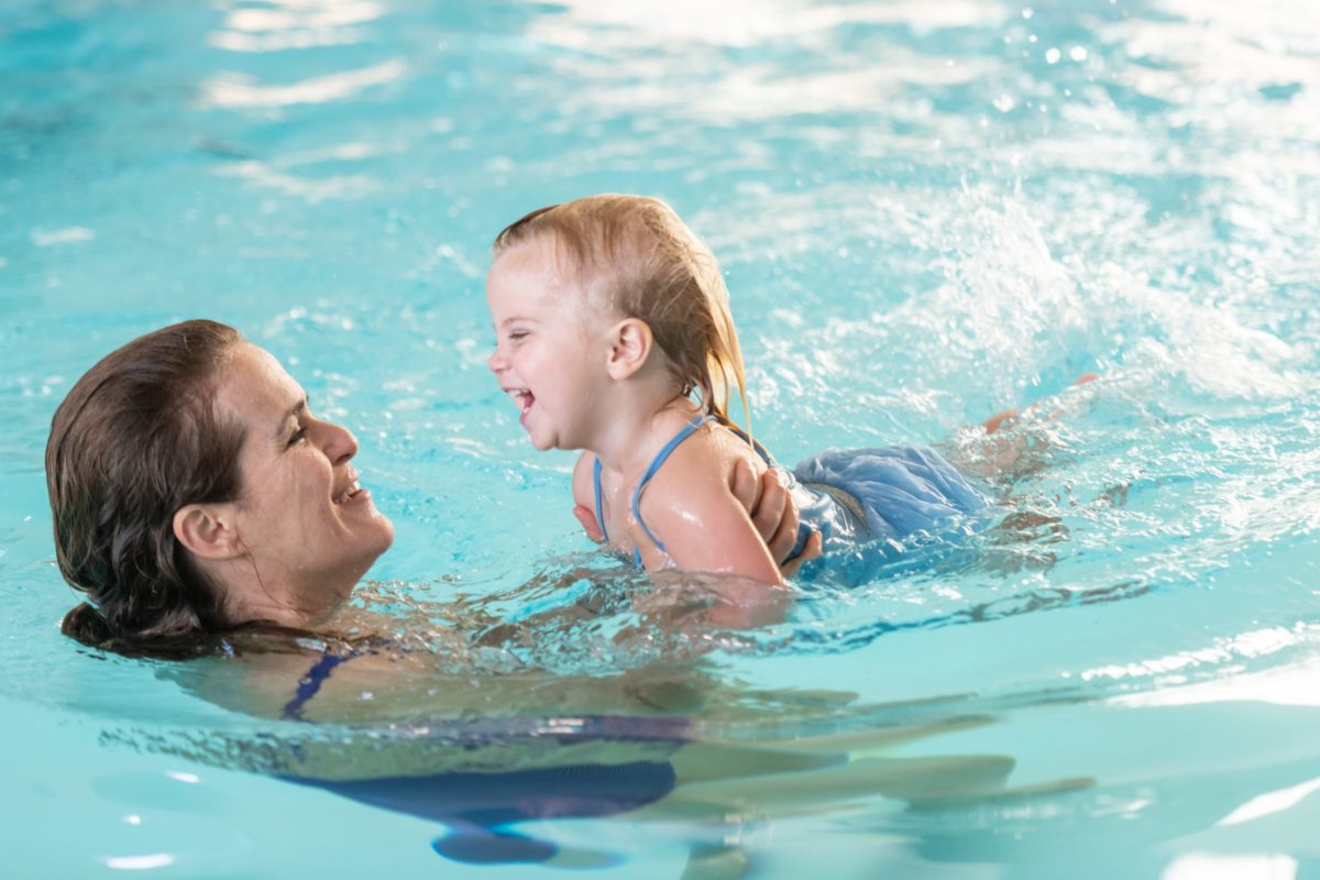 Mature woman playing with her daughter in the swimming pool